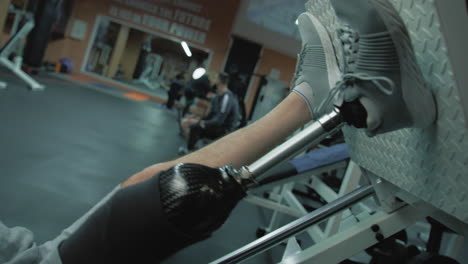 Tracking-shot-of-motivated-athlete-with-prosthetic-leg-training-on-leg-press-machine-in-modern-gym.-Adult-sporty-man-with-artificial-limb-does-strength-workout-using-professional-sports-equipment.